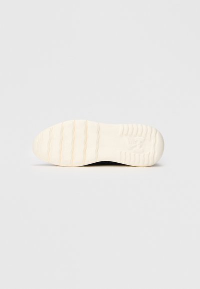 Semelle de chaussure en caoutchouc blanc texturé avec un motif ondulé et un logo en relief, conçue pour l'adhérence et la durabilité.