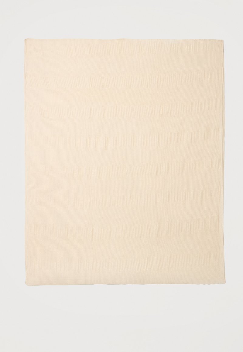 Carré de tissu beige avec une texture subtile à côtes verticales sur un fond uni et clair.