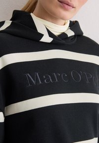 Black and cream striped hoodie with a soft texture, featuring an embroidered logo "Marc O'Polo" on the front. Hooded design.