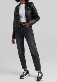 Musta nahkainen biker-takki, valkoinen t-paita, mustat korkeavyötäröiset farkut ja massiiviset mustat lenkkarit, joissa valkoiset yksityiskohdat. Räätälöity istuvuus, lyhyt malli.