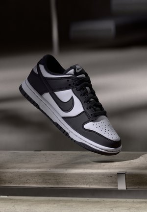 Sneaker in bianco e nero con tomaia in pelle, punta perforata, collo imbottito e suola in gomma con dettagli testurizzati.