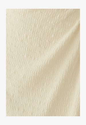 Tissu de couleur crème avec un motif texturé subtil comportant de petites lignes verticales et horizontales en relief, créant un effet de grille douce.