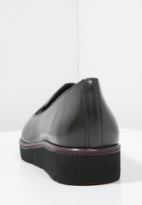 Scarpe in pelle nera con finitura liscia, punta arrotondata e suola nera bassa e testurizzata. Presentano cuciture sottili e una silhouette elegante.