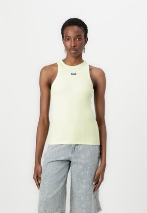  hellgrün gestreiftes Tanktop mit rundem Halsausschnitt und ärmellosem Design. Verfügt über ein kleines blaues Logo auf der Brust. Kombiniert mit Jeansshorts.