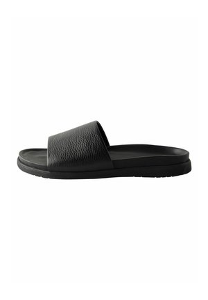 Black slide sandals with a textured leather upper, open toe design, and a flat rubber sole. The style is minimalist and modern.