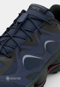 Blå Merrell tursko med mesh-overdel, gummidetaljer og Gore-Tex-merke. Designet inkluderer lagdelte teksturer og slanke konturer.