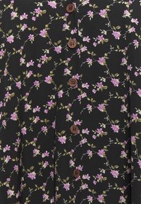 Tela negra con un estampado floral en púrpura y verde, con botones marrones en el centro. Patrón detallado de flores y hojas.