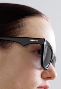 Óculos de sol pretos em acetato com armação grossa e design angular. Logótipo dourado "MISSONI" na parte das hastes. Lentes escuras.