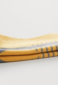 Textile jaune à motif avec des accents gris, mettant en valeur un tissage texturé et un design plié, avec des rayures horizontales et une finition lisse.