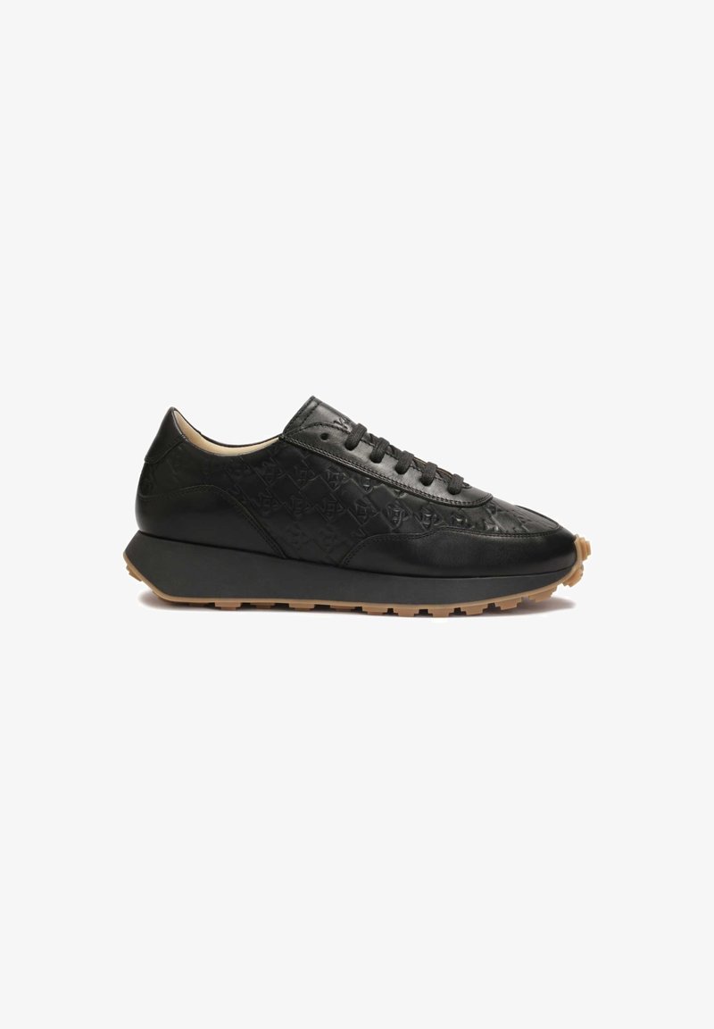 Sneaker en cuir noir avec un dessus en cuir texturé, un col rembourré et une semelle en caoutchouc, présentant un design minimal de laçage.