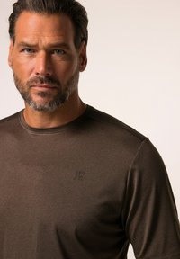 Brun kortærmet t-shirt lavet af glat stof, med rund halsudskæring og subtilt logo på brystet, flade sømme og uden mønstre.