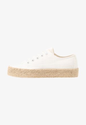 White canvas sneaker with a textured finish, featuring a woven jute sole, round toe, and six eyelets with metallic eyelets.