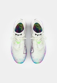 White athletic shoes with multi-colored gradient soles, textured fabric upper, and contrasting black and green accents. Tied laces visible.