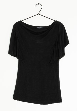 Sort bluse med korte ærmer, bred halsudskæring og flagrende ærmer, hængende på en tynd sort bøjle mod en hvid baggrund.
