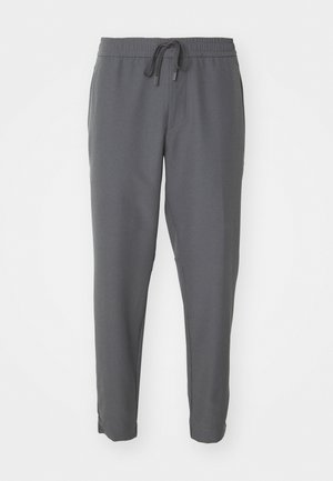 Calças de fato cinzas feitas de tecido suave, apresentando uma cintura elástica com cordão, pernas ajustadas e bolsos laterais.