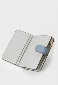 Portefeuille en cuir gris clair avec une fermeture à pression bleue, des emplacements pour cartes à l'intérieur et un compartiment zippé. Texture lisse avec un léger éclat.