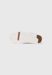 White sneaker sole with textured rubber for grip, featuring a brown accent and curved designs. Flat profile with circular and zigzag patterns.