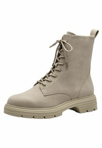 Beige-nahkainen nyörillinen saapas, jossa pyöreä kärki, vahvistetut saumat ja paksu kumipohja, jossa on kuvioitu kuvio.