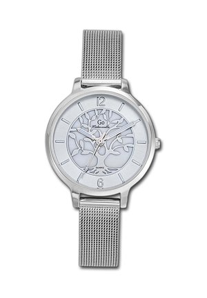 Montre en quartz argentée avec un bracelet en mailles. Le cadran rond présente un fond blanc avec un motif d'arbre et des index horaires argentés aux positions 12 et 6.