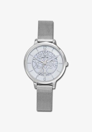 Montre en quartz argentée avec un bracelet en mailles. Le cadran rond présente un fond blanc avec un motif d'arbre et des index horaires argentés aux positions 12 et 6.