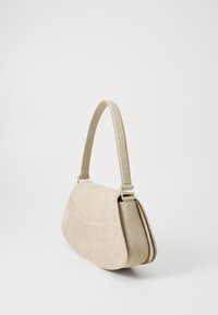 Bolsa de ombro bege com um acabamento em camurça texturizada, forma curva, ferragens em tom dourado e uma alça única para facilitar o transporte.