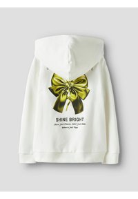 Valge kapuutsiga pusa, millel on suur roheline lipsu graafika ja tekst "SHINE BRIGHT." Disainitud kapuutsiga ja soonikkoes varrukate äärtega, et anda vabaaja välimus.