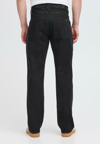 Jeans de denim negro con corte recto, que cuentan con dos bolsillos traseros y una cinturilla. El material tiene un ligero estiramiento y una textura suave.