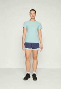 Lys blå trenings-T-skjorte kombinert med marineblå shorts med lys blå aksent. Antrekket fullføres med svarte joggesko og hvite sokker.