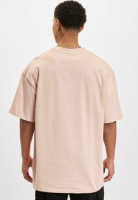 Lyser�ød oversized t-shirt lavet af blødt stof med korte ærmer, en rund hals og et enkelt, rent design. Ingen mønstre eller accenter.