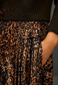 Sukně s leopardím vzorem v hnědých a černých barvách, se stahovacím pasem a bočními kapsami. Texturovaná látka kombinuje hladkost s luxusním pocitem.