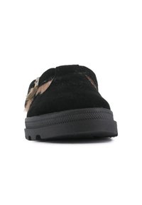 Chaussure slip-on noire en daim avec une semelle en caoutchouc texturée et une accent en fourrure beige, présentant un détail en métal décoratif.