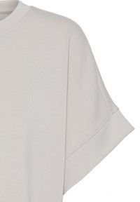 T-shirt ample à manches courtes de couleur gris clair avec ourlet large et encolure ronde, présenté sur un fond blanc.