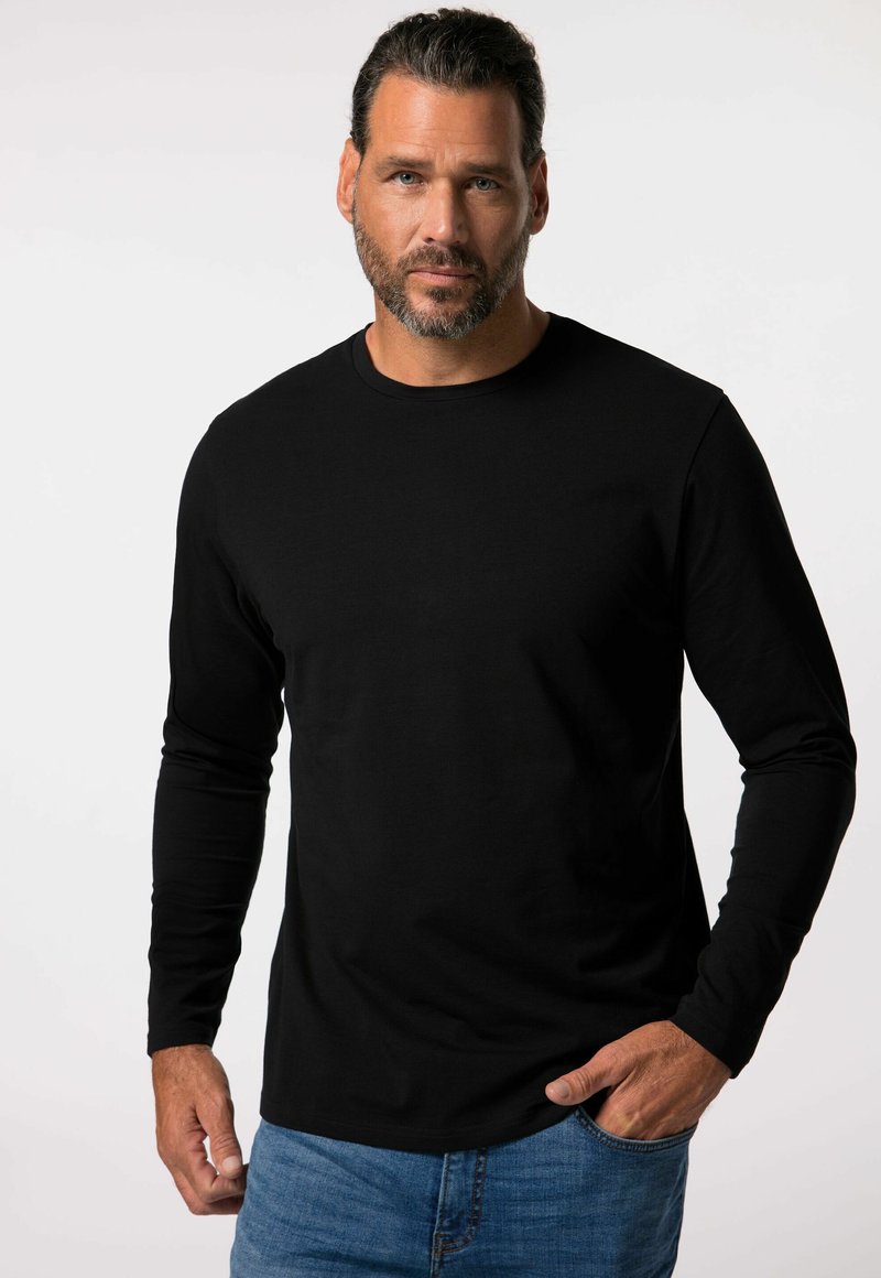 Schwarzes Langarmshirt aus glattem Stoff mit rundem Ausschnitt und taillierter Silhouette. Kombiniert mit blauen Jeans.