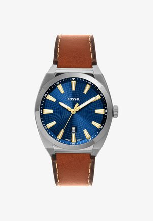 Men's Fossil wristwatch with blue textured dial, gold hour markers and hands, date window at 6 o'clock, and brown leather strap.