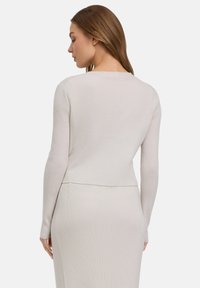 Hellgrauer, gerippter Strickpullover mit langen Ärmeln, rundem Ausschnitt und verkürztem Saum, kombiniert mit einem passenden gerippten Rock.