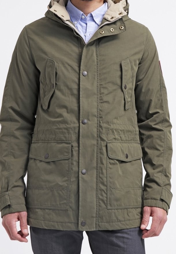 Olive green parka jacket with a beige hood, two front pockets, snap buttons, and a cinched waist. Textured fabric with a casual design.