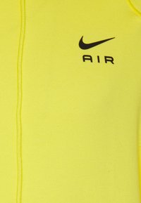 Ljusgul hoodtröja med svart "Nike AIR"-logotyp, tillverkad av mjukt material, med en slät textur och en klassisk design.