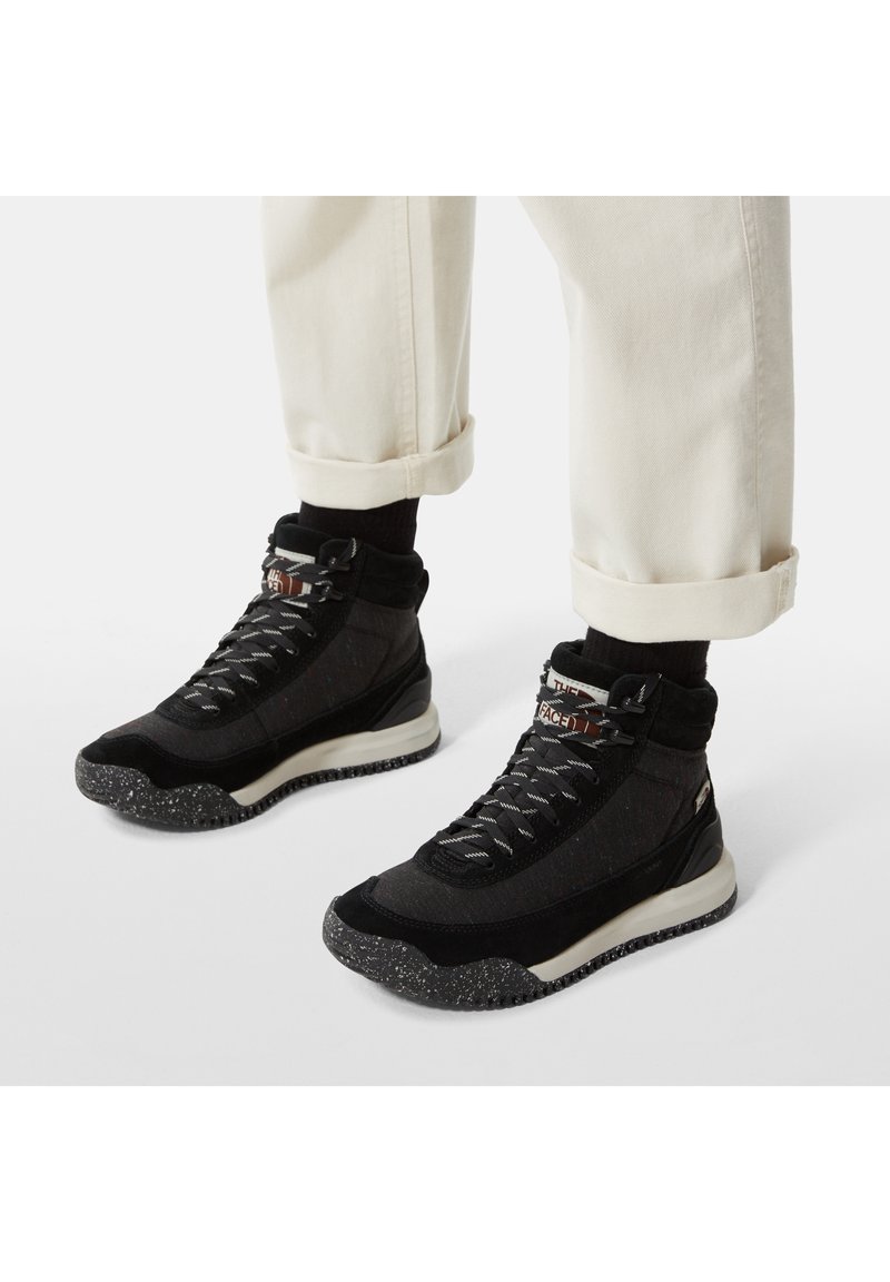 Svarta högskor med en texturerad ovandel, ljusgrå detaljer och prickiga yttersulor. Utrustad med snörning och en vadderad krage för stöd.