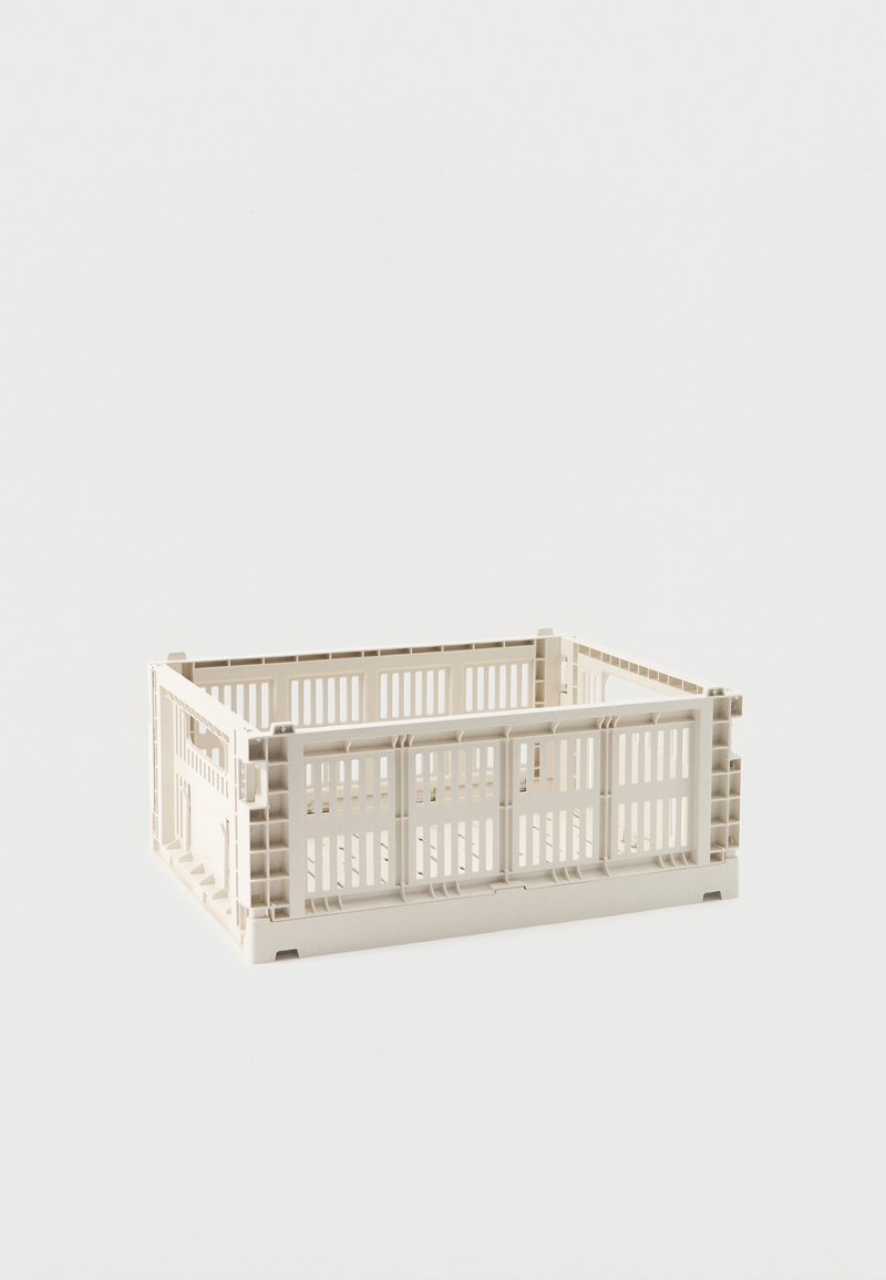 Πτυσσόμενο πλαστικό καλάθι σε μπεζ χρώμα με πλευρές που αερίζονται και λαβές, άδειο και τοποθετημένο σε λευκή επιφάνεια.