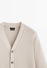 Cardigan en tricot beige clair avec col en V côtelé et deux boutons foncés sur le devant, présenté sur fond blanc.