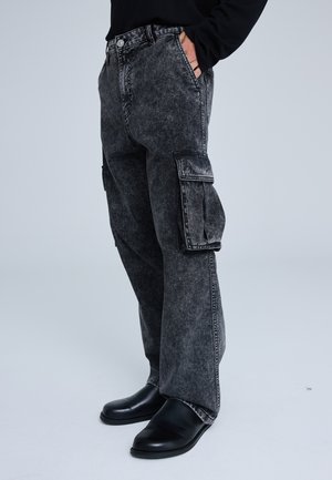 I jeans cargo in denim nero presentano una finitura sbiadita, tasche laterali, una vestibilità dritta e una chiusura a bottone con una vita classica.