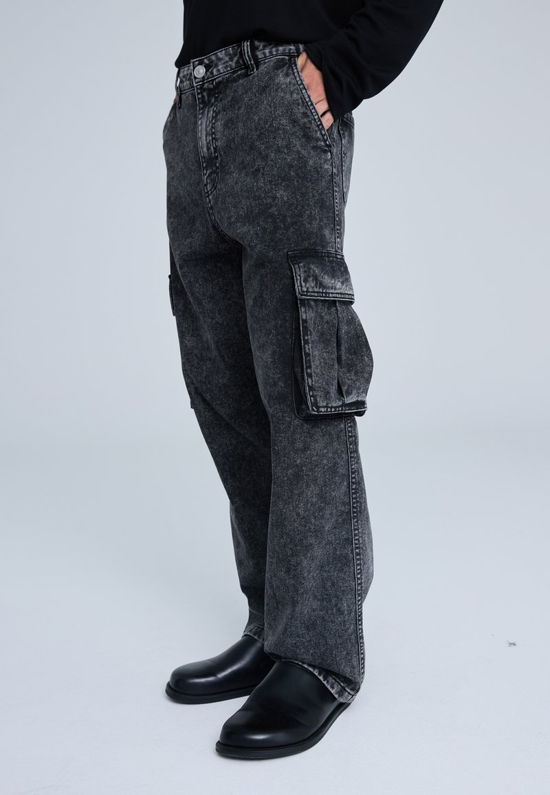 I jeans cargo in denim nero presentano una finitura sbiadita, tasche laterali, una vestibilità dritta e una chiusura a bottone con una vita classica.