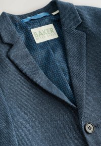 Blazer azul marino texturizado con cuello con muesca, cierre de botones y forro interior azul con estampado. La etiqueta muestra "BAKER by Ted Baker".