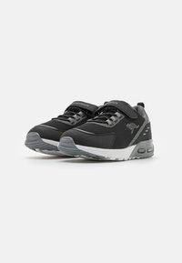Schwarze Sportschuhe mit einem Mesh-Obermaterial, grauen Akzenten, Schnürsenkeln und einem Klettverschluss. Dicke weiße Sohle mit sichtbaren Dämpfungselementen.