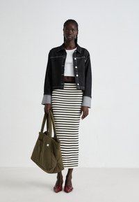 Giubbotto di jeans nero con polsini grigio chiaro, top corto bianco, gonna a righe a costine, borsa a tracolla verde oliva e scarpe rosse con punta.