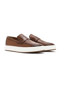 Mocasines de cuero marrón con una tira ancha en la parte superior, detalles de costura y una suela de goma blanca para dar contraste.