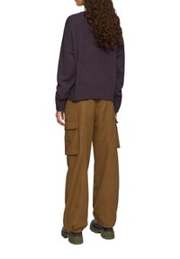 Trui in donkerpaars, oversized fit met geribbelde onderrand; gecombineerd met losse, bruine cargobroek met zijzakken en een gladde textuur.