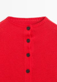 Červený pletený cardigan s vysokým límcem a pěti černými knoflíky vpředu. Textura je hladká s elastickým povrchem.