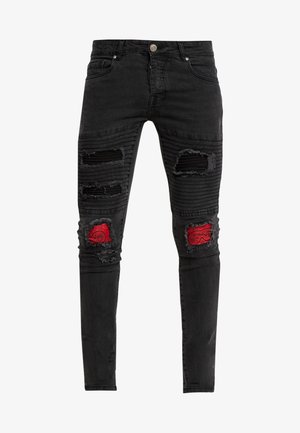 Black denim jeans with distressed details, ribbed accents on the thighs, and red paisley patches on both knees. Slim fit design.