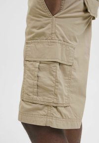 Khaki cargo shorts featuring side pockets, a relaxed fit, and a textured, durable fabric with visible stitching details.